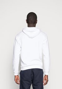 Witte hoodie met een trekkoordcapuchon, geribde manchetten en onderrand, zachte textuur en een losse pasvorm. Gezicht vanaf de achterkant.