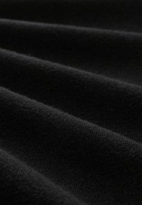 Schwarzer Stoff mit einer weichen, strukturierten Oberfläche, der sanfte Falten und ein glattes Finish zeigt. Das dehnbare Material erhöht den Komfort und die Vielseitigkeit.