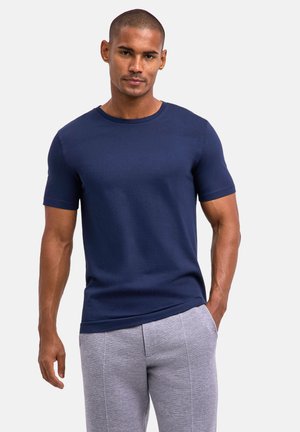 T-shirt azzurro scuro a maniche corte in tessuto morbido, design con colletto girocollo e silhouette aderente, abbinato a pantaloni della tuta grigi chiari.