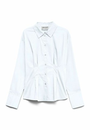 Chemise blanche à manches longues avec col pointu et plis subtils à la taille, présentée à plat sur un fond blanc.