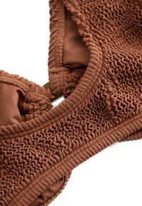 Brown textured fabric bikini top with ruched knit design and padded cups on a white background.