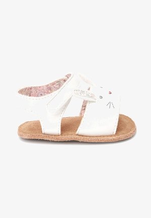 Sandales blanches en matériau synthétique avec une semelle texturée marron. Présentent un design de visage de lapin avec des oreilles et une doublure florale rose.