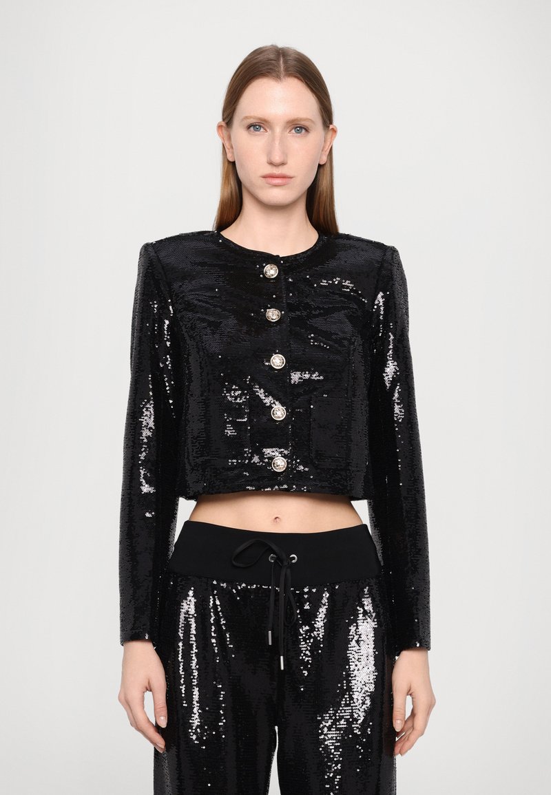 Black cropped sequin jacket with long sleeves, round neckline, five silver buttons, and two front pockets. Paired with black sequin pants.