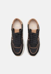 Paire de baskets noires et marron à lacets avec semelles blanches et marquage BOSS à l'intérieur et sur la languette, vues de dessus.