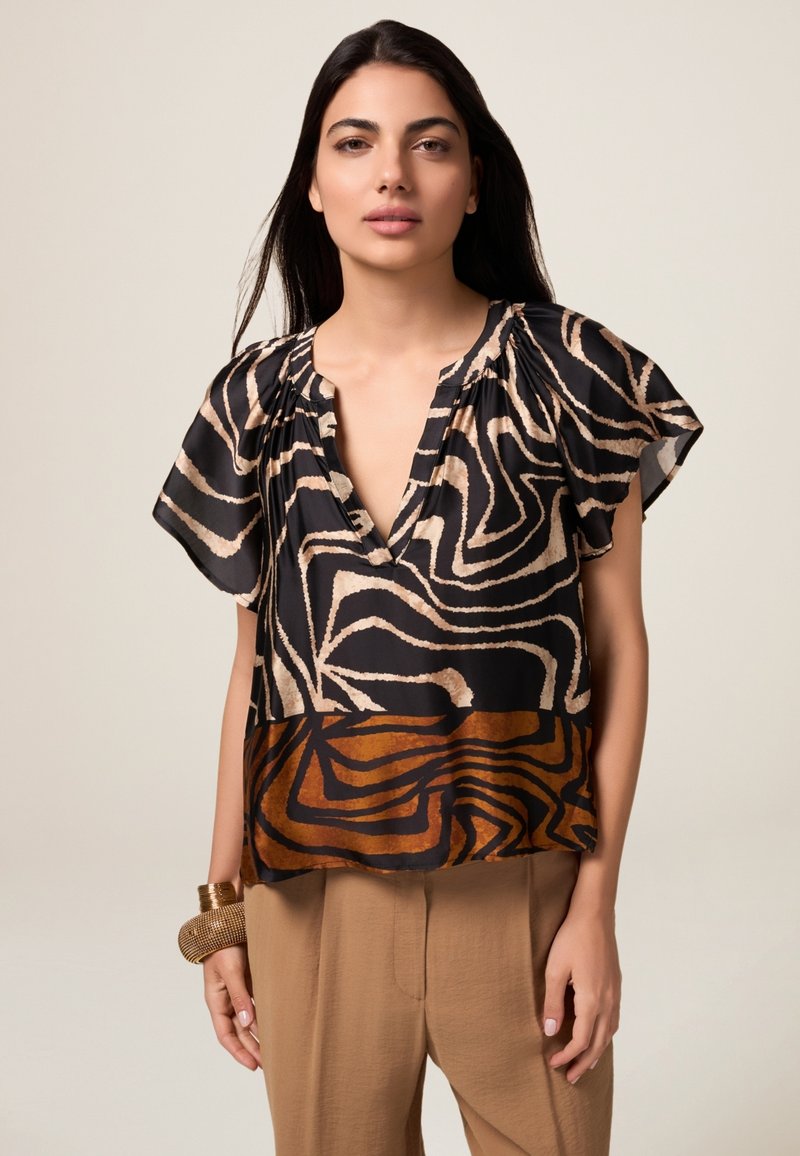 Blouse à manches courtes avec une base noire ornée de tourbillons abstraits beiges et bruns, décolleté en V et tissu fluide pour un ajustement décontracté.