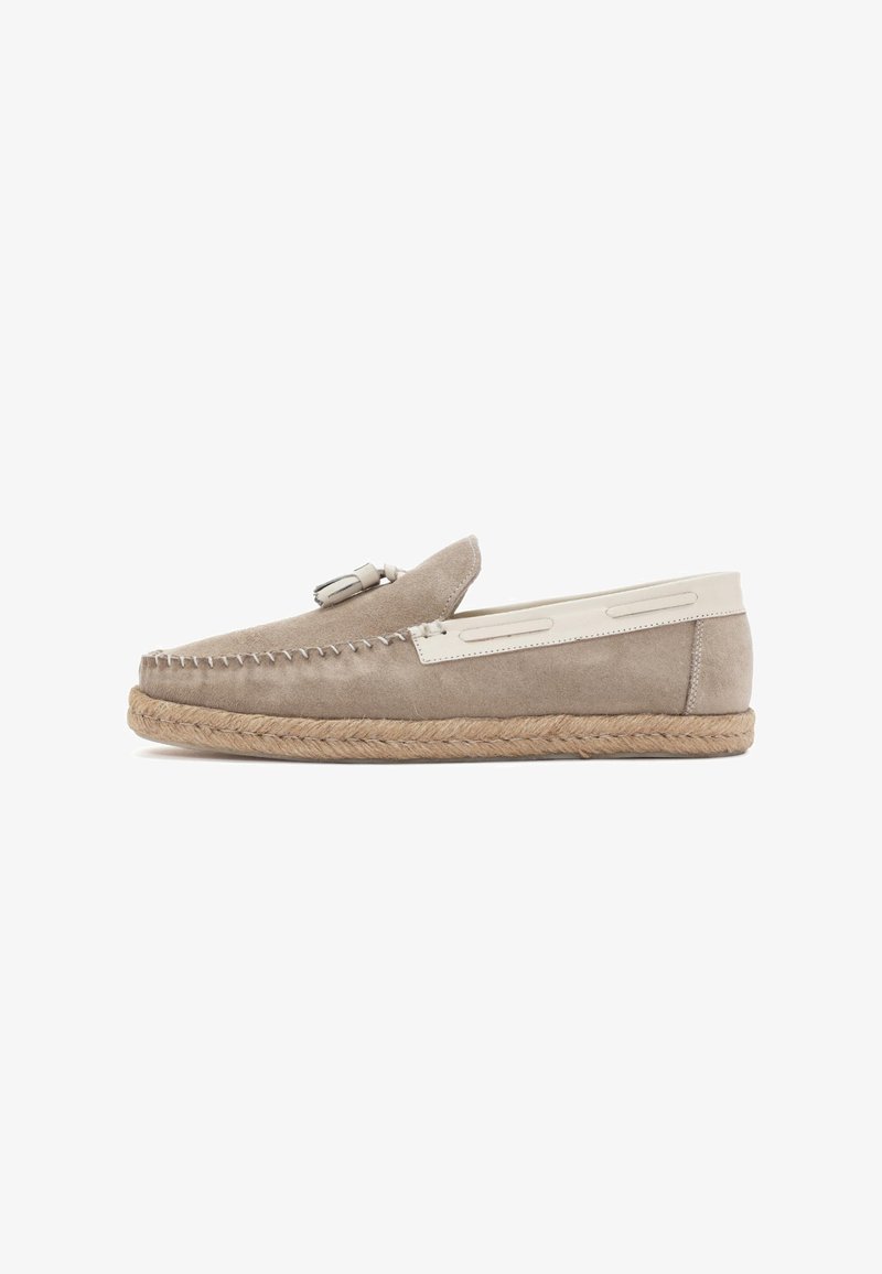 Mocasines de ante en tono topo con acentos en crema, una suela de yute trenzada, costuras decorativas y un pequeño borlón decorativo en la parte superior.