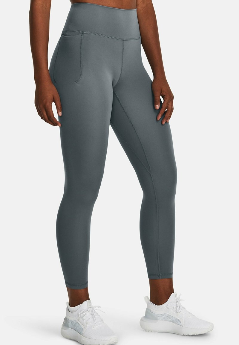 Leggings grigi con vita alta, dotati di tasche laterali e realizzati in un tessuto liscio ed elastico. Il design include dettagli di texture sottili.