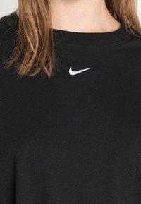 Svart bomull t-shirt med rund hals och korta ärmar, med en liten vit Nike-logotyp broderad på övre vänster bröst.
