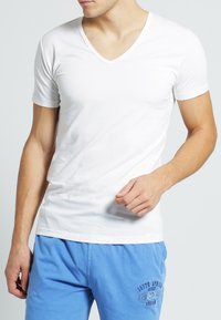 T-shirt bianca a maniche corte con scollo a V realizzata in tessuto di cotone liscio, design aderente, con una silhouette semplice e senza motivi o accenti visibili.