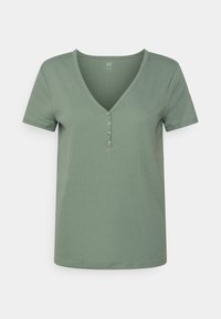 T-shirt vert en V en tissu doux, avec des manches courtes et un détail de bouton au niveau du cou. Texture lisse avec une coupe décontractée.