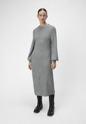 Abito grigio a coste con maniche lunghe a puffo e scollatura rotonda. Indossato con stivali neri con tacco spesso. Design minimalista.