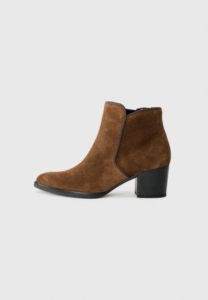 Stivaletto in suede marrone con tacco a blocco nero e zip laterale, esposto su uno sfondo bianco puro.