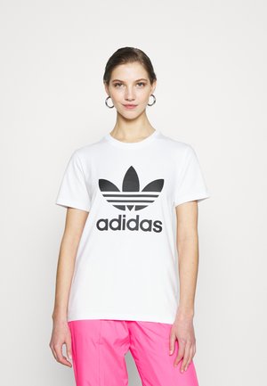 Hvit bomulls t-skjorte med en stor svart Adidas-logo med trefoil-design. Korte ermer og klassisk rund hals.