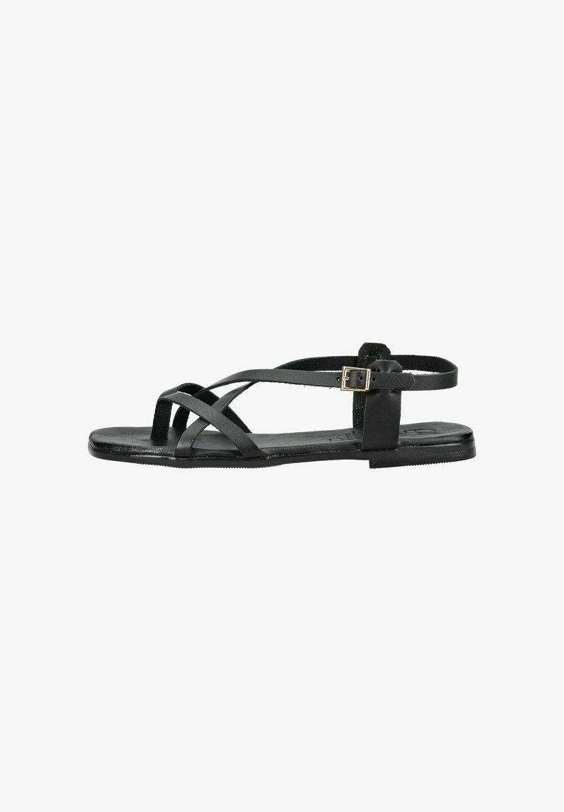 Sandale plate noire avec de fines lanières en cuir qui croisent le pied, bride de cheville avec boucle dorée et boucle pour l'orteil.