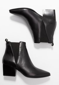 Schwarze Lederstiefeletten mit spitz zulaufender Zehenpartie und elastischen Seitenpaneelen. Mit einem Blockabsatz und einer Zuglasche an der Rückseite für einfaches An- und Ausziehen.