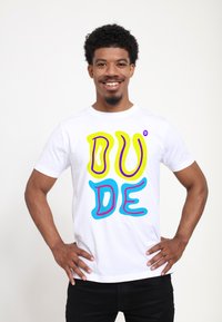 Bílý bavlněný tričko s barevným grafickým textem "DUDE" v žluté, modré a růžové barvě. Krátké rukávy, kulatý výstřih, běžný střih.