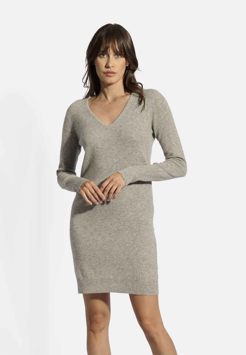 Abito grigio lavorato a maglia con scollatura a V, maniche lunghe e polsini a coste. Il tessuto sembra morbido e testurizzato, con una silhouette aderente.