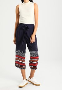 Marina culotter med texturerad tyg, prydda med horisontella ränder i röd, vit och brun. Knut i midjan och ankellångda med elastiska muddar.