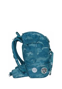 Sac à dos bleu-vert avec un motif de camouflage pixélisé, des bretelles réglables, une fermeture en cordon en haut et un patch rond sur le côté.