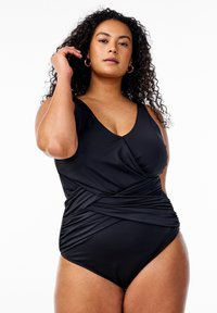 Maillot de bain une pièce noir avec un décolleté en V, des détails froncés à la taille et des bretelles larges. Fabriqué en matériau doux et extensible.
