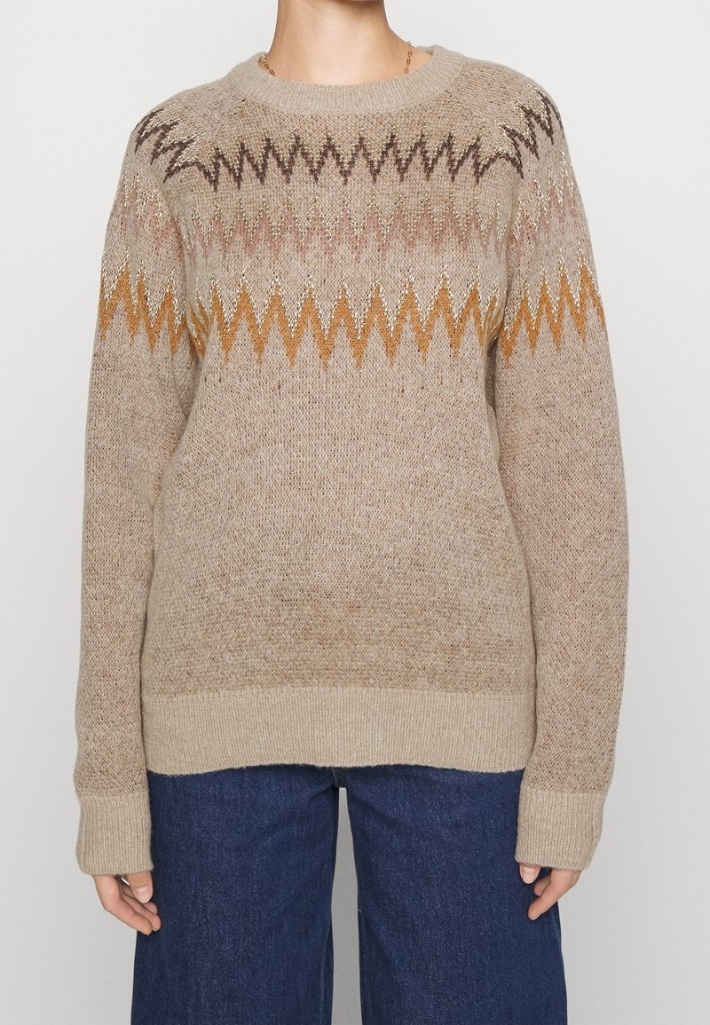 Beżowy sweter dzianinowy z zygzakowym wzorem w brązowym, złotym i rdzawym kolorze, z okrągłym dekoltem i ściągaczem na dole, wykonany z teksturowanej tkaniny.