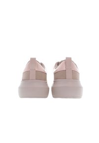 Paire de baskets beige et rose vues de dos, montrant des semelles épaisses et des languettes au talon sur fond blanc.