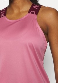 Růžový atletický top s hladkou texturou, vybavený širokými bordó ramínky s bílým nápisem. Přiléhavý design, bez rukávů.