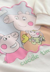 Rysunkowe świnie na białej tkaninie; jedna trzyma żółtą gumową kaczkę, mała świnka w zielonych piżamach, tekst "czas na tulenie" częściowo widoczny.