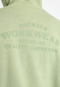 Ανοιχτό πράσινο φούτερ με απαλή υφή, που διαθέτει εκτυπωμένο κείμενο: "Dickies Workwear Από το '22 Ποιοτικά Ρούχα" σε θαμπό πράσινο.