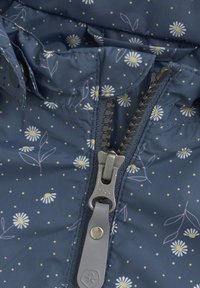 Marinblå jacka med blommönster och prickar, med en central dragkedja med ett silverfärgat dragöglan och hög krage. Mjuk, strukturerad tyg.