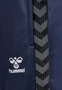 Marineblauwe sportshorts met een zwarte geweven streep met een chevronpatroon en een wit 'hummel' logo aan de linkerkant.