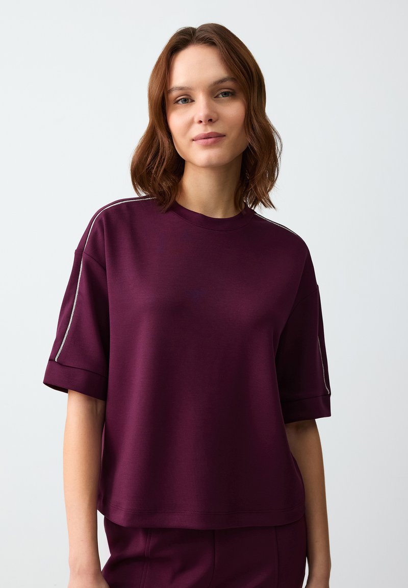 Bordeauxkleurig T-shirt met korte mouwen, gemaakt van zachte stof en met een relaxte pasvorm, voorzien van zilveren accenten langs de schoudernaden.