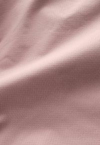 Texturerad tyg i mjuk rosa, med ett subtilt rutmönster. Materialet verkar slätt med en lätt glans och faller mjukt.