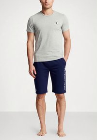 Grå rundhalset t-skjorte kombinert med marineblå shorts med hvit logotrykk på siden. Begge laget av bomullsblanding, med en avslappet passform.