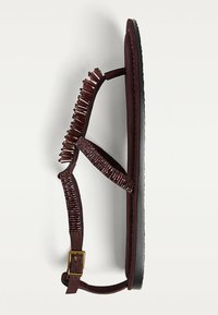 Sandales bordeaux avec des détails en perles complexes, semelle plate, fines lanières et fermeture à boucle dorée. Tissu texturé et cuir lisse.