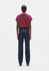 Burgundy short-sleeve t-shirt with a crew neck paired with high-waisted, straight-leg blue denim jeans featuring two back pockets.