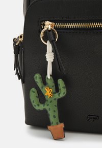 Bolso negro texturizado con cremallera dorada, que presenta un charm en forma de cactus verde con una base marrón y bordados amarillos.
