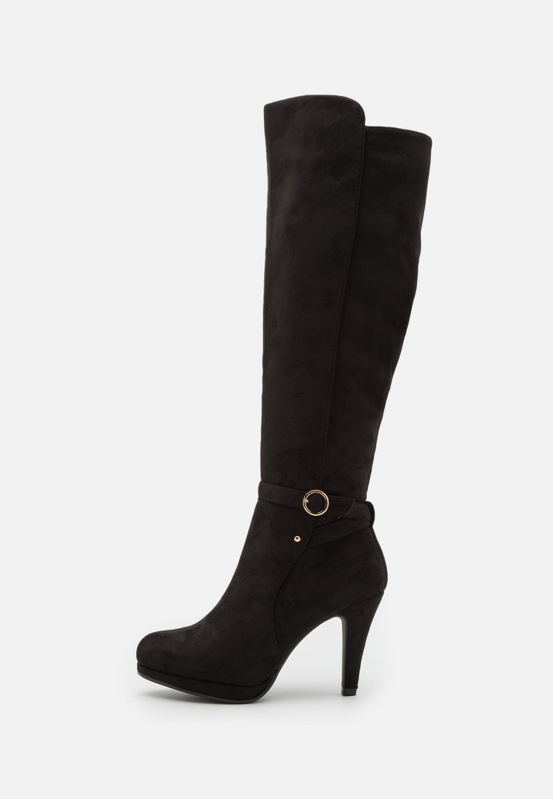 Botas negras de ante sobre la rodilla, con un alto tacón de aguja, tira en el tobillo con un detalle de anillo dorado y una textura suave.