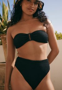 Svart virkat bikini-set med en bandeau-topp med twist fram och högmidjade byxor. Texturerat tyg med en slät finish.