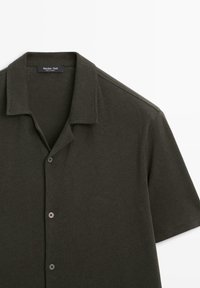 Short-sleeve dark olive green polo shirt with camp collar and three buttons, made from soft knit fabric.