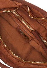 Interno di una borsa a tracolla in pelle marrone con più scomparti con cerniera, hardware dorato e foderato in tessuto. Etichetta del marchio visibile.