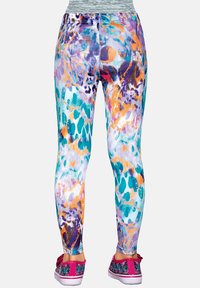 Nogi w kolorowych leginsach o abstrakcyjnym wzorze w kolorach fioletowym, pomarańczowym, turkusowym i białym, zestawione z różowymi i czarnymi trampkami w kwiaty.