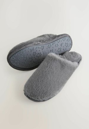 Grå päls tofflor med en fluffig ovansida och texturerad gummisula med stjärn- och halvmånemönster. Öppen bakdesign för enkel på- och avtagning.
