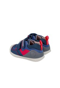 Zapatos infantiles azules y rojos con tiras de velcro, parte superior de tela texturizada, suela de goma y acentos contrastantes para estabilidad y comodidad.
