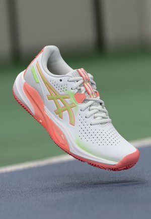 Sneaker bianco con design in mesh, accenti neon brillanti e suola rosa. Perforazioni sulla tomaia per traspirabilità.