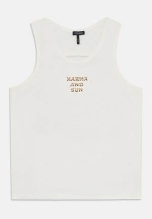 Hvit tanktopp laget av myk stoff, med gullbroderi som leser "KARMA AND SUN" sentrert foran. Klassisk formet design.