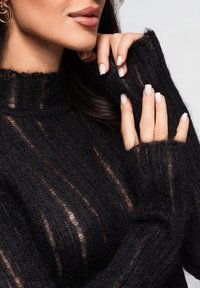 Maglione nero lavorato a maglia con collo alto, caratterizzato da strisce trasparenti e maniche lunghe, con una texture morbida e un design aderente.