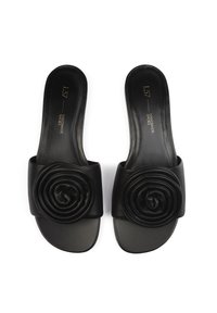 Infradito nere con una fascia ampia che presenta un design a spirale. Realizzate in pelle liscia con una suola piatta e una branding minima.