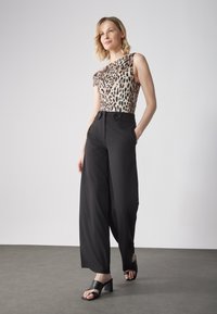 Body a manica corta con stampa leopardata, abbinato a pantaloni neri a vita alta e gamba larga, con dettagli in bottone e spacchi all'orlo.