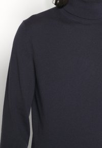 Dunkelblauer Rollkragenpullover mit strukturiertem Strickmuster, figurnah geschnitten und mit langen Ärmeln, aus einem weichen Stoff gefertigt.